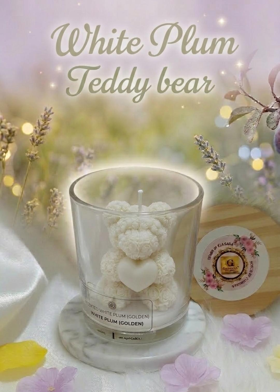 White plum teddy bear candle in a glass container with decorative elements on a soft background.