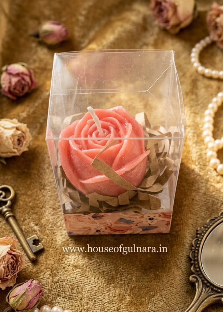 Pink rose-shaped soap in a clear box on a textured surface with pearls and a key.