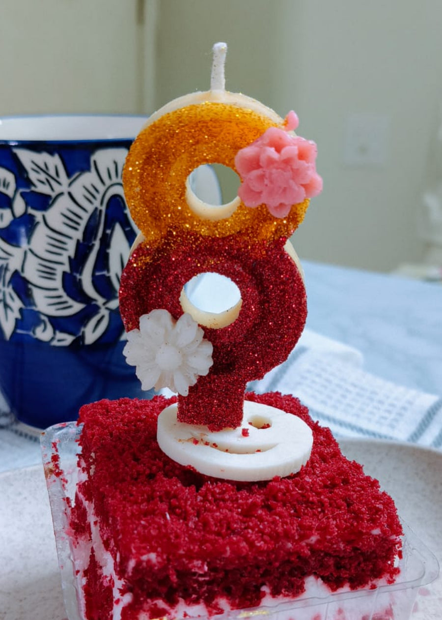 Red velvet cake with a small Santa Claus candle on a white plate.