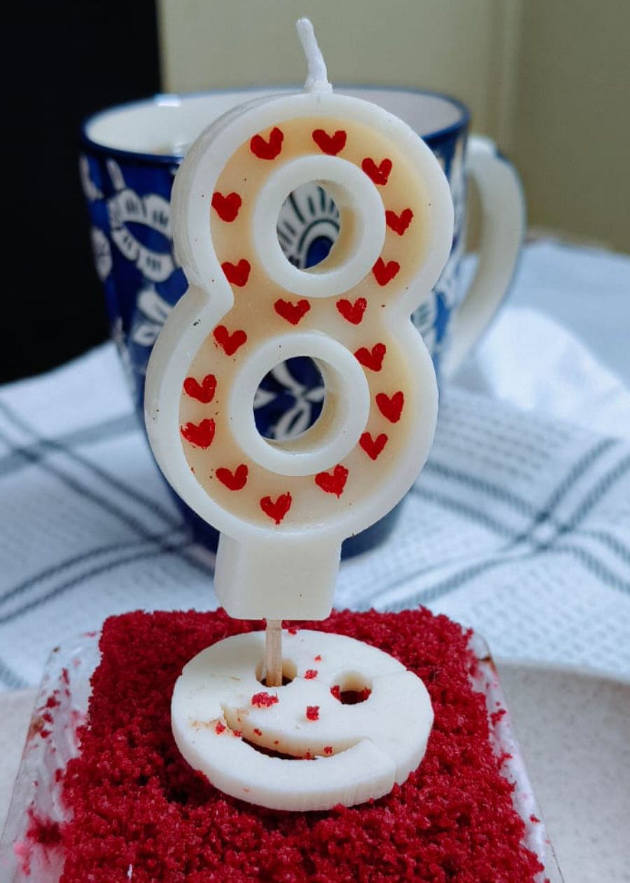 Small red velvet cake with a number 8 candle on a white plate.