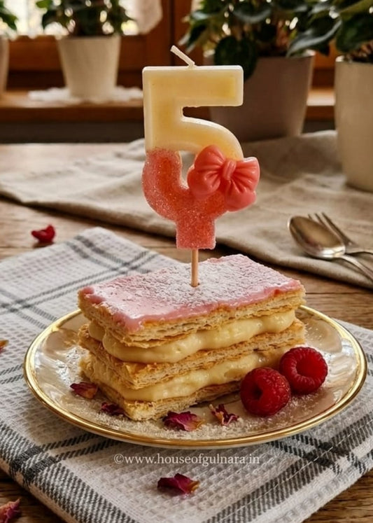 Pastry with a number 5 candle on a table with flowers in the background