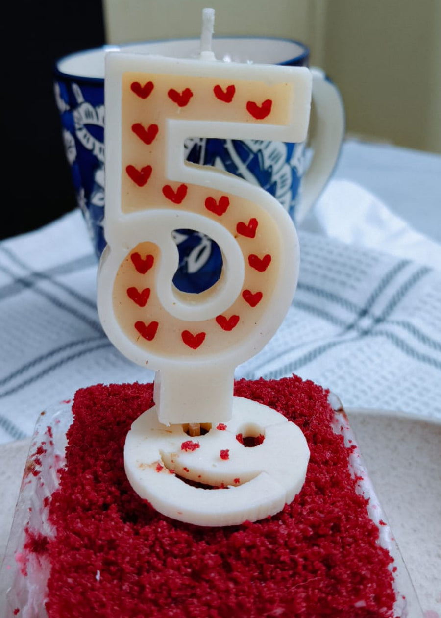 Number 5 candle on a red cake with a blurred background