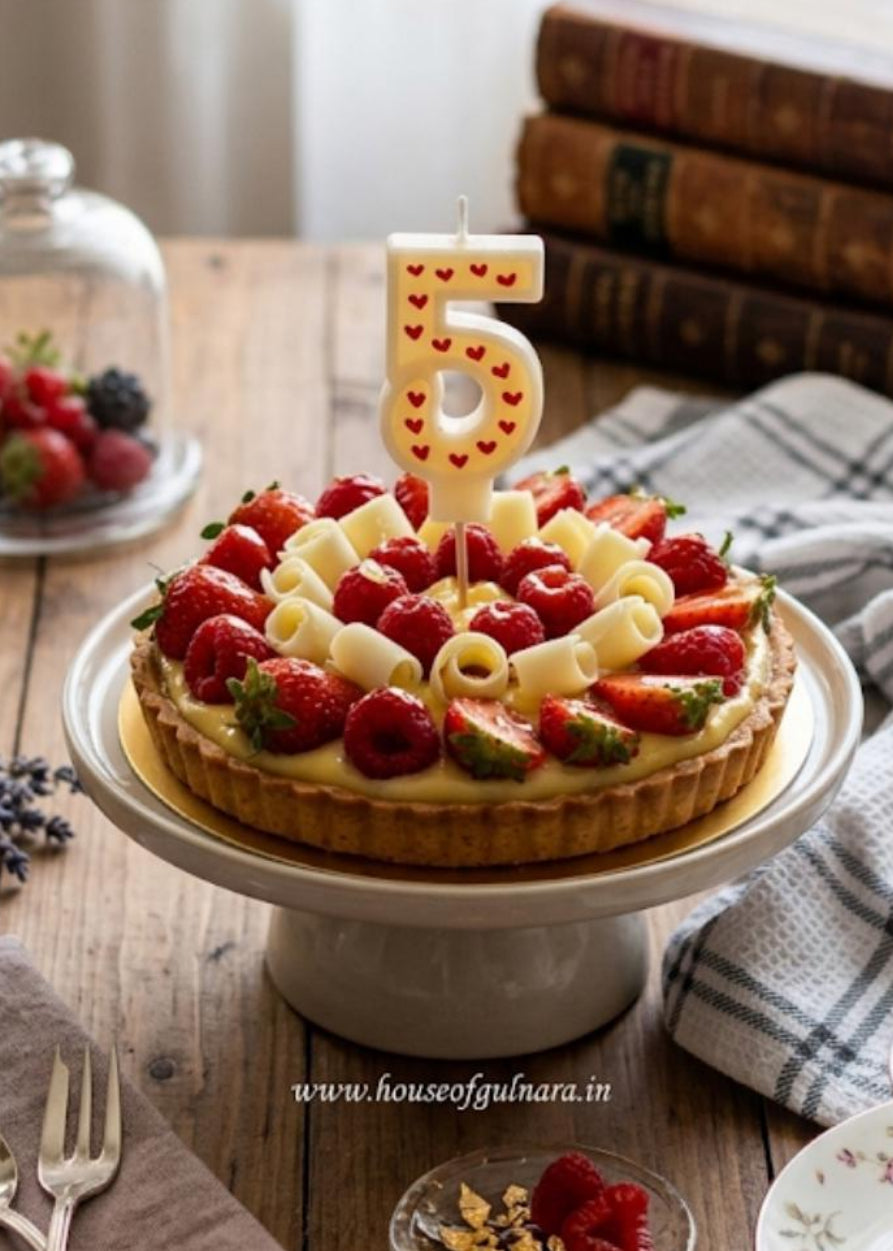 Decorative cake with strawberries and a number 5 candle on a wooden table with books and tea set.