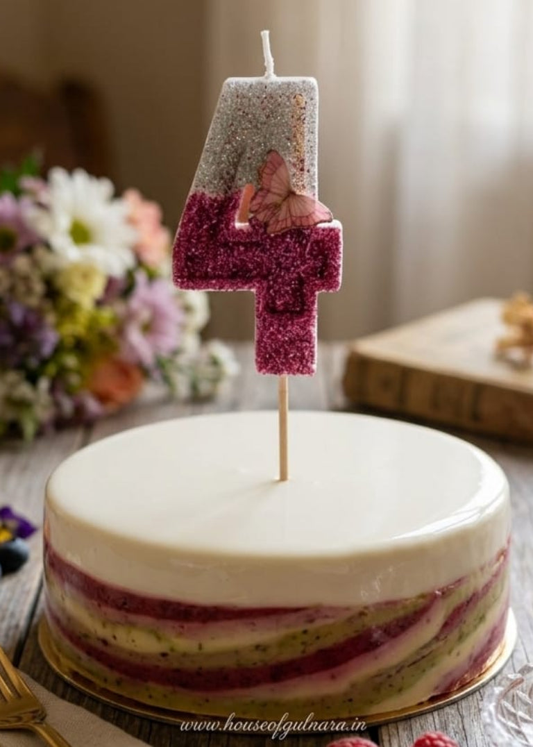 Decorative cake with a number 4 candle on a wooden table with flowers and cutlery.
