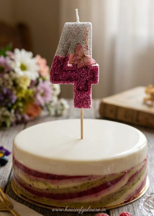 Decorative cake with a number 4 candle on a wooden table with flowers and cutlery.
