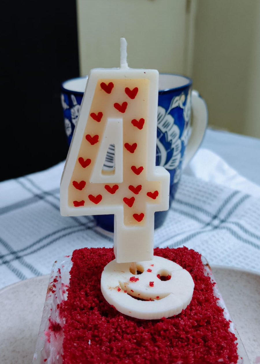 Red velvet cake with a number 4 candle on a table.