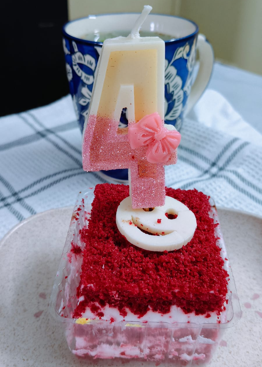 Small red velvet cake with a number 4 candle on a white plate.