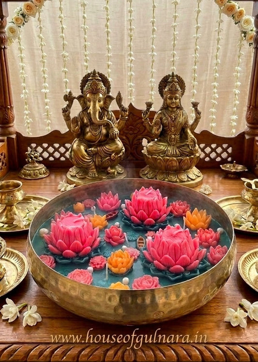 Decorative setup with statues and colorful lotus-shaped candles on a wooden table.