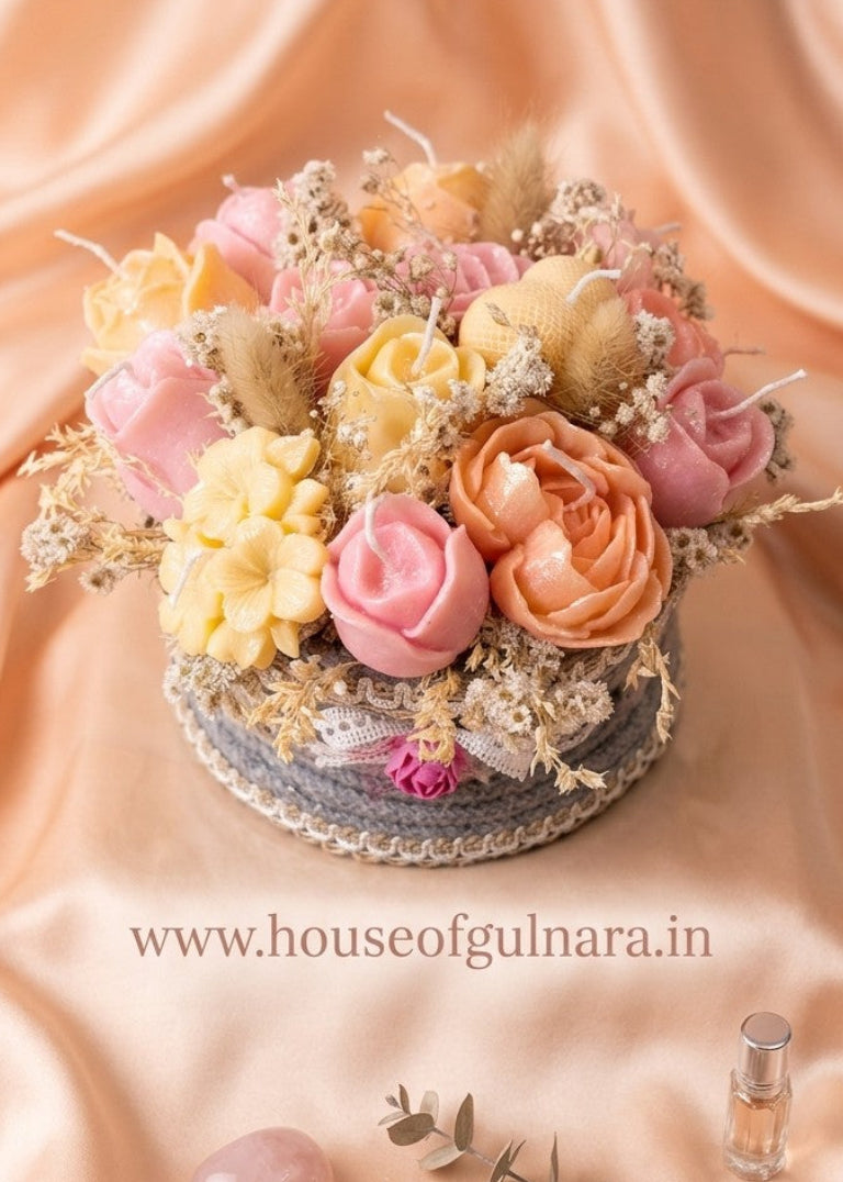 Decorative candle flower arrangement with candles on a peach fabric background, featuring 'www.houseofgulnara.in'.