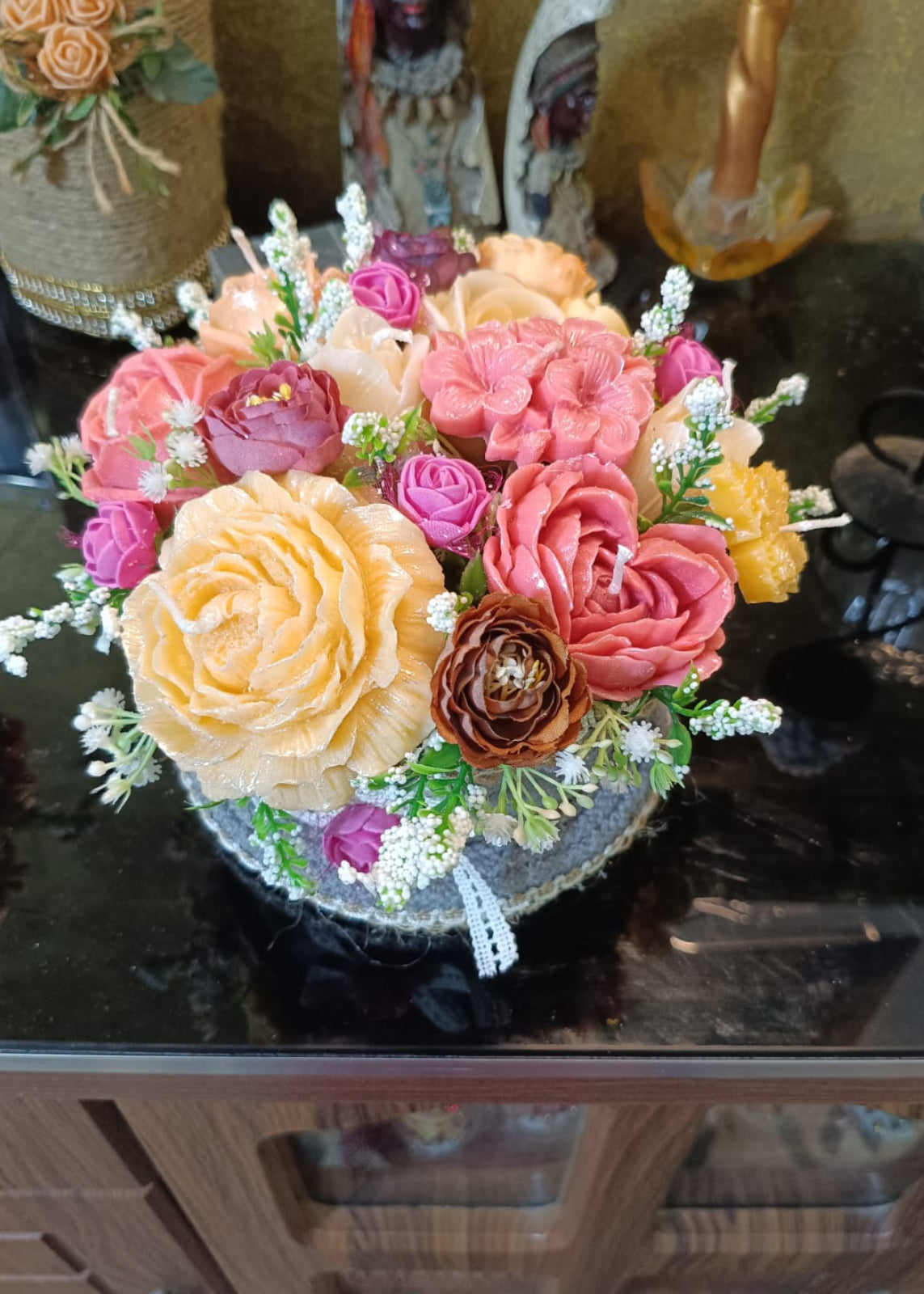 Colorful candle  flower arrangement on a reflective surface with decorative background