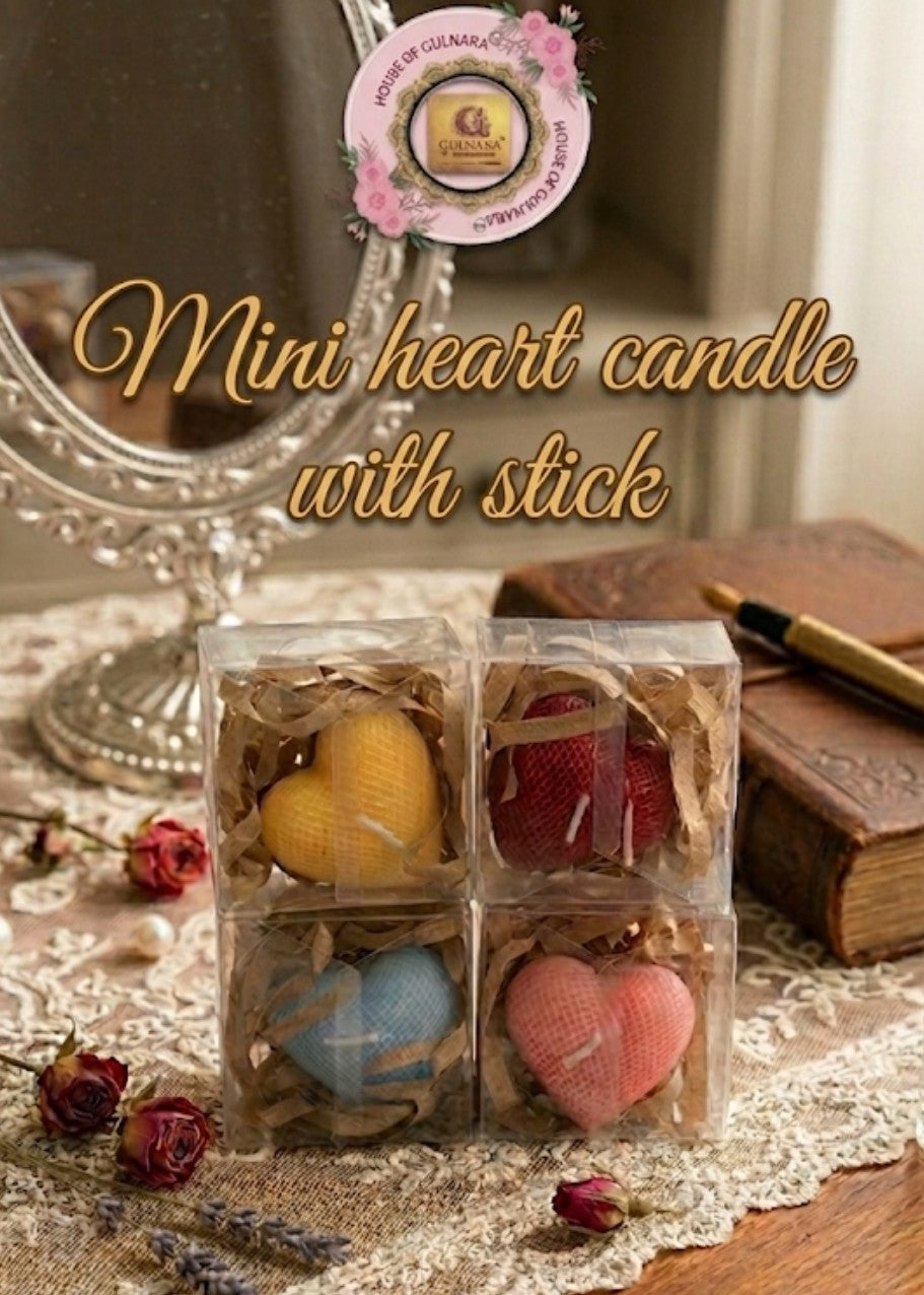 Mini heart candles with sticks in clear packaging on a decorative surface with a book and pen.