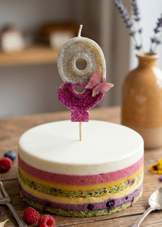 Layered cake with a pink number '1' candle on a wooden table with berries and a vase in the background.