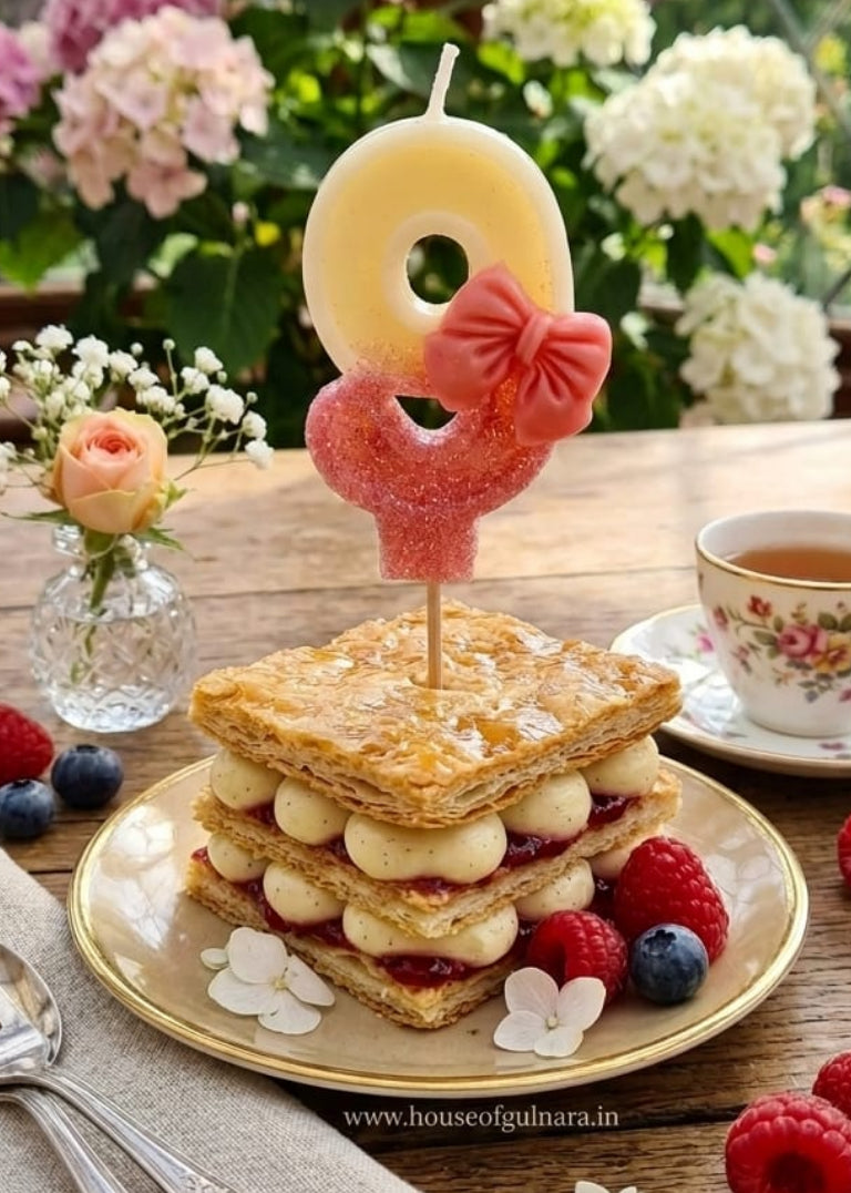 Stack of sandwiches with a number 9 candle on a wooden table with flowers and tea.