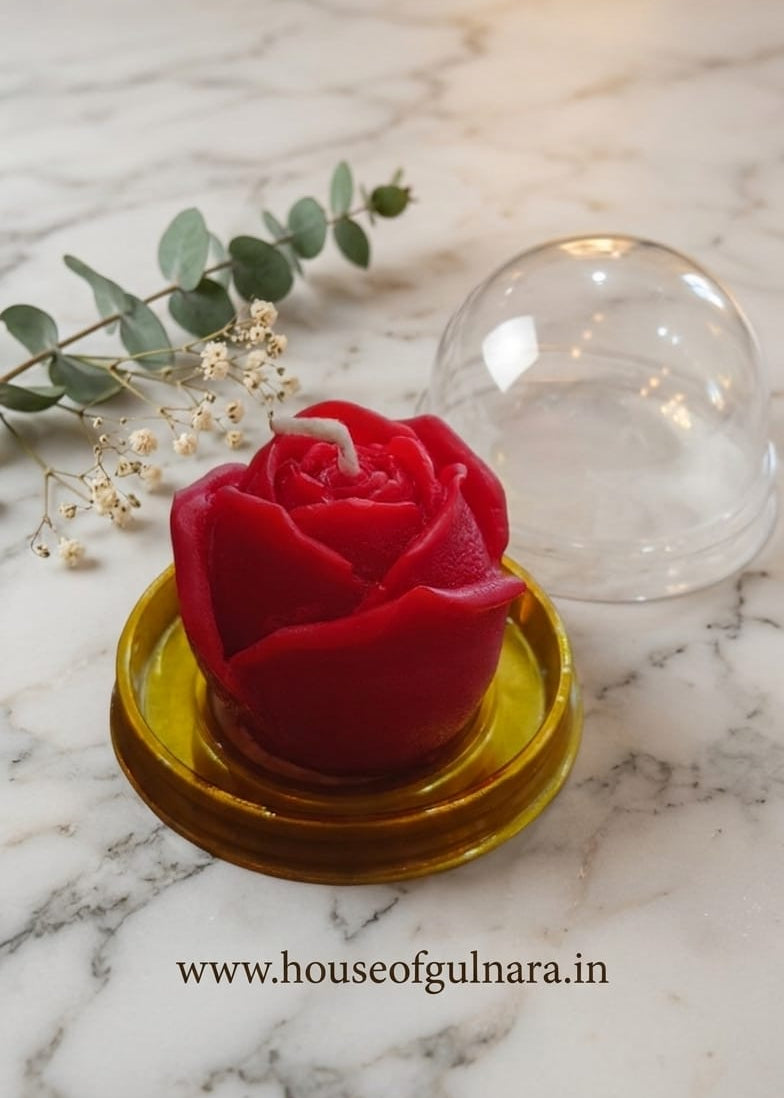 Red rose-shaped candle on a yellow coaster with a marble background and 'www.houseofgulnara.in' branding.
