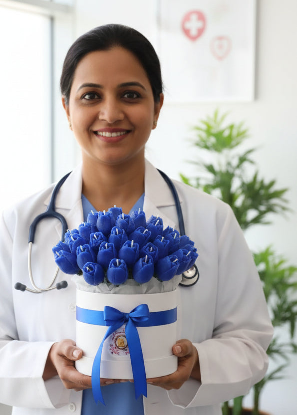 Bouquet of blue artificial tulip candle flowers in a decorative box on a wooden surface.