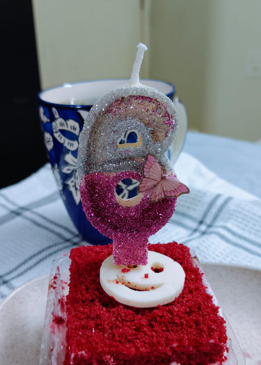 Red velvet cake with a decorative candle on a white plate