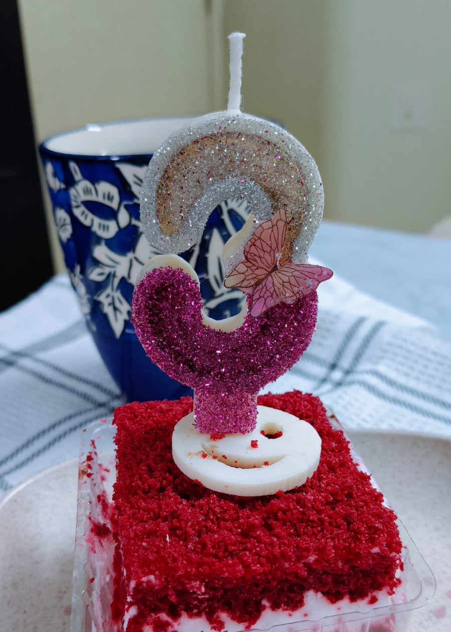 Small red velvet cake with a decorative candle on a white surface