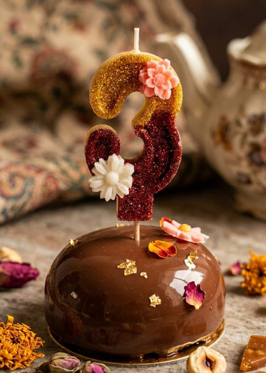 Chocolate cake with a number 2 candle and decorative elements on a rustic surface.