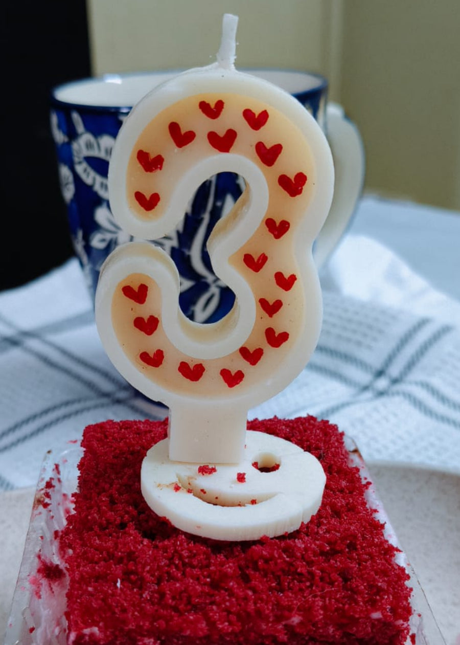Small red velvet cake with a number 8 candle on a white plate.