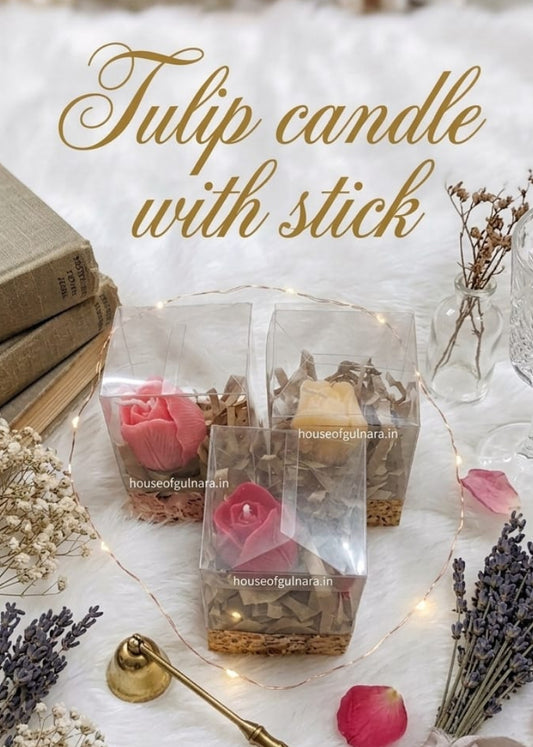 Tulip candle with stick on a decorative surface with flowers and a book.