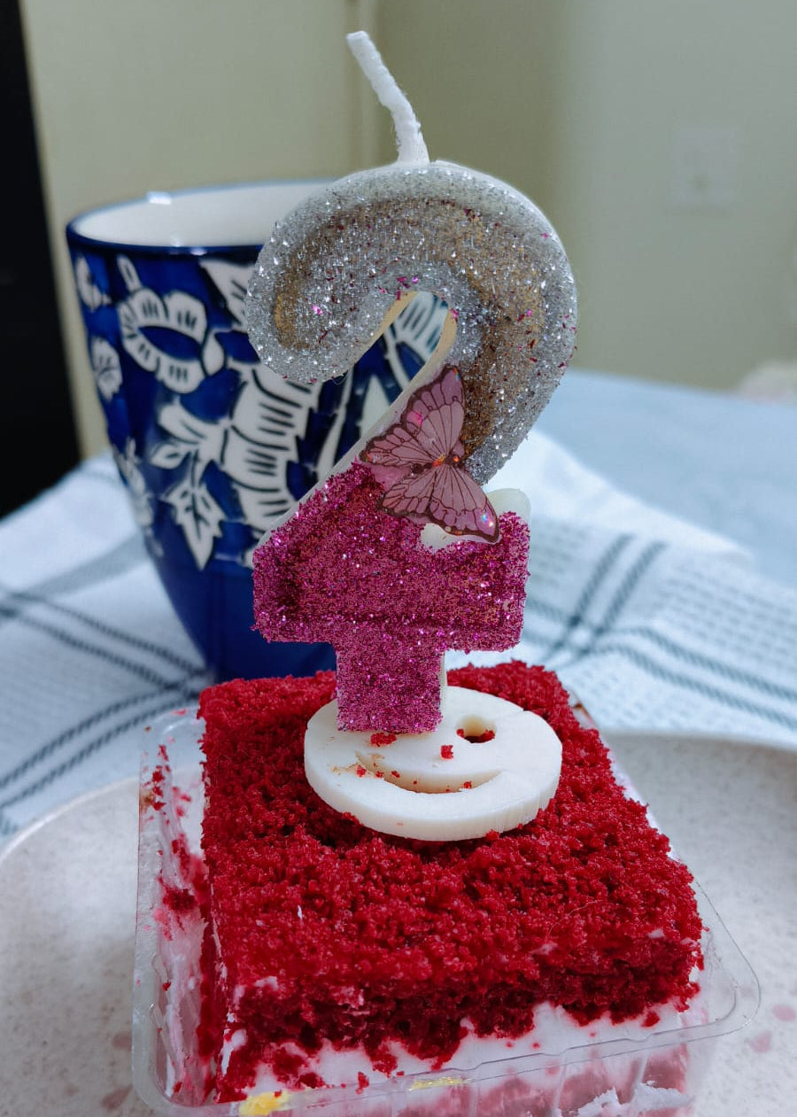 Small red velvet cake with a number 1 candle on a white plate.