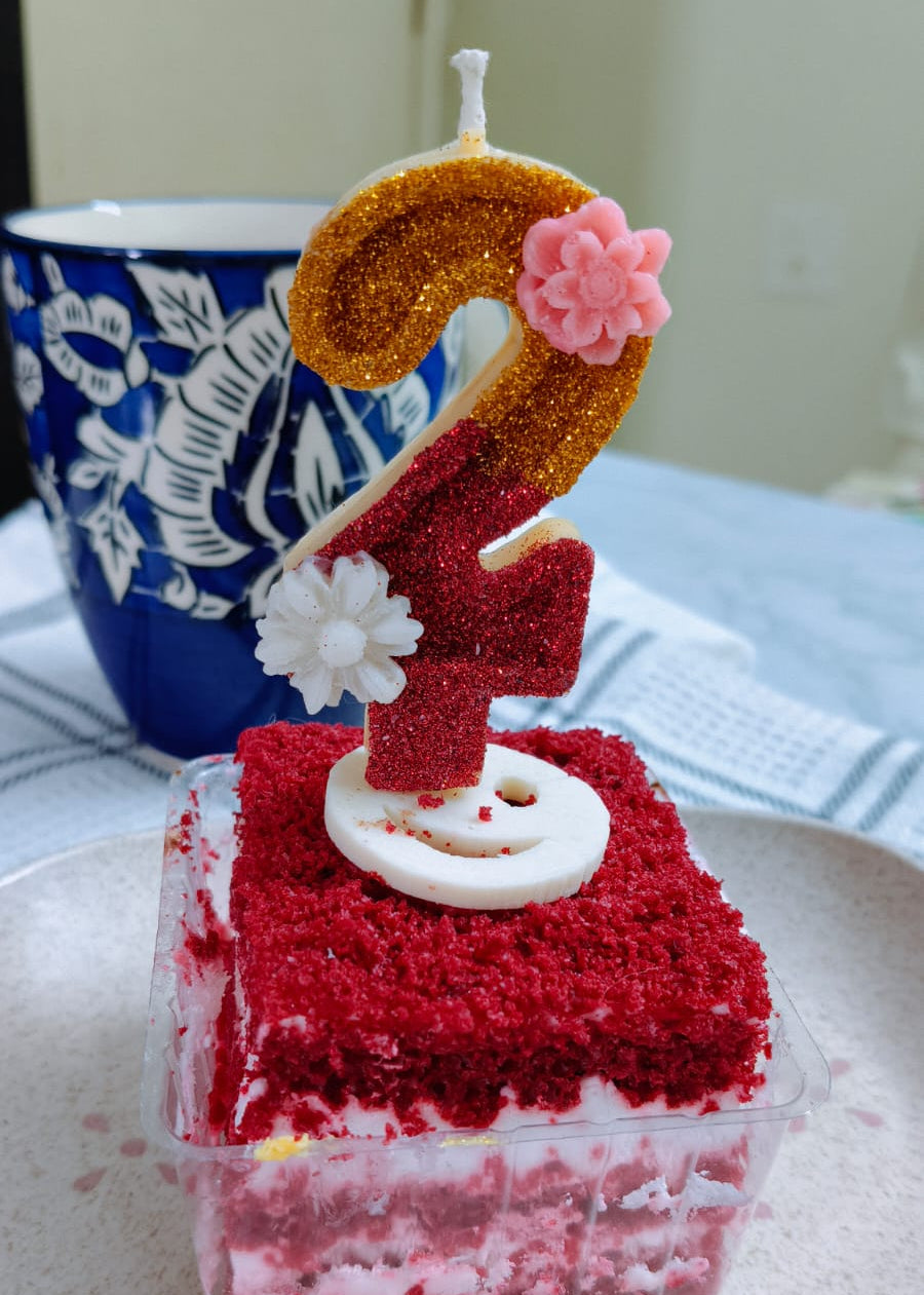Small red velvet cake with a number two candle on a white plate.