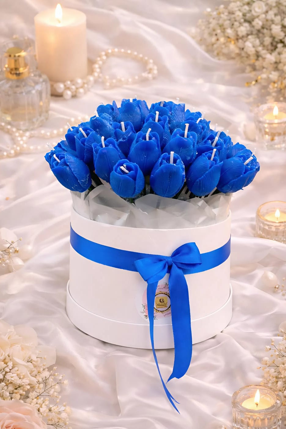 Blue tulip-shaped candles in a white box with a blue ribbon on a decorative background.