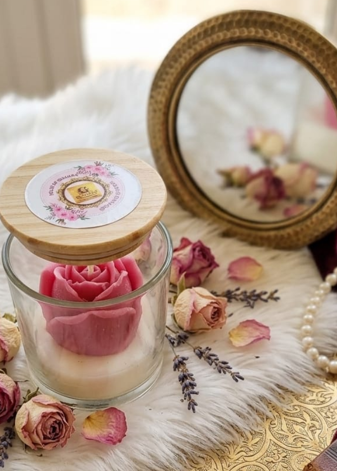 Decorative scene with a glass jar of pink roses, wooden box, and floral elements on a textured surface.