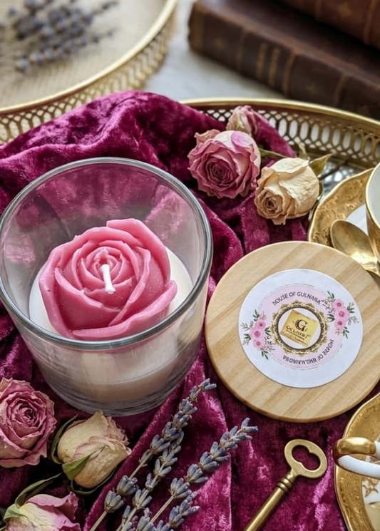 Decorative setting with pink rose candle, key, and books on a textured surface