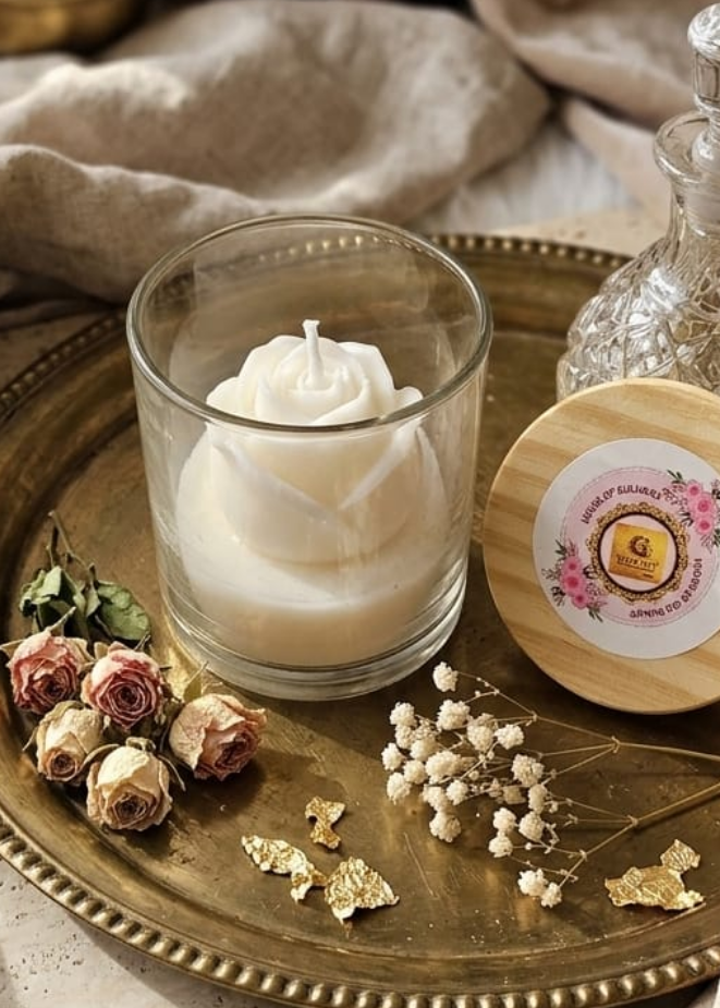 Decorative setting with a white rose  candle, flowers, and books on a textured surface.