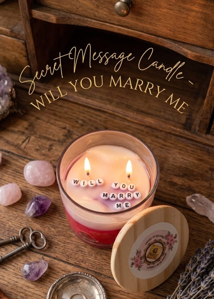 Candle with 'Will You Marry Me' message on a wooden surface with crystals and keys.