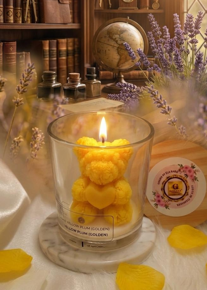 Candle shaped like a bear in a glass holder on a table with lavender and books in the background