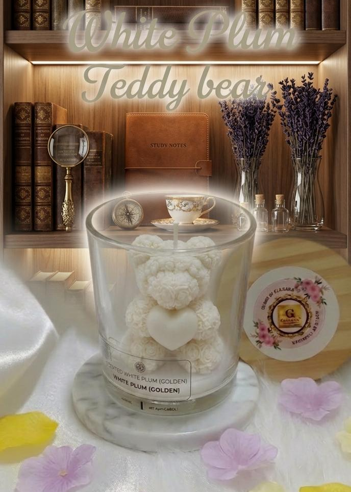 Candle with a white teddy bear design on a shelf with books and flowers.