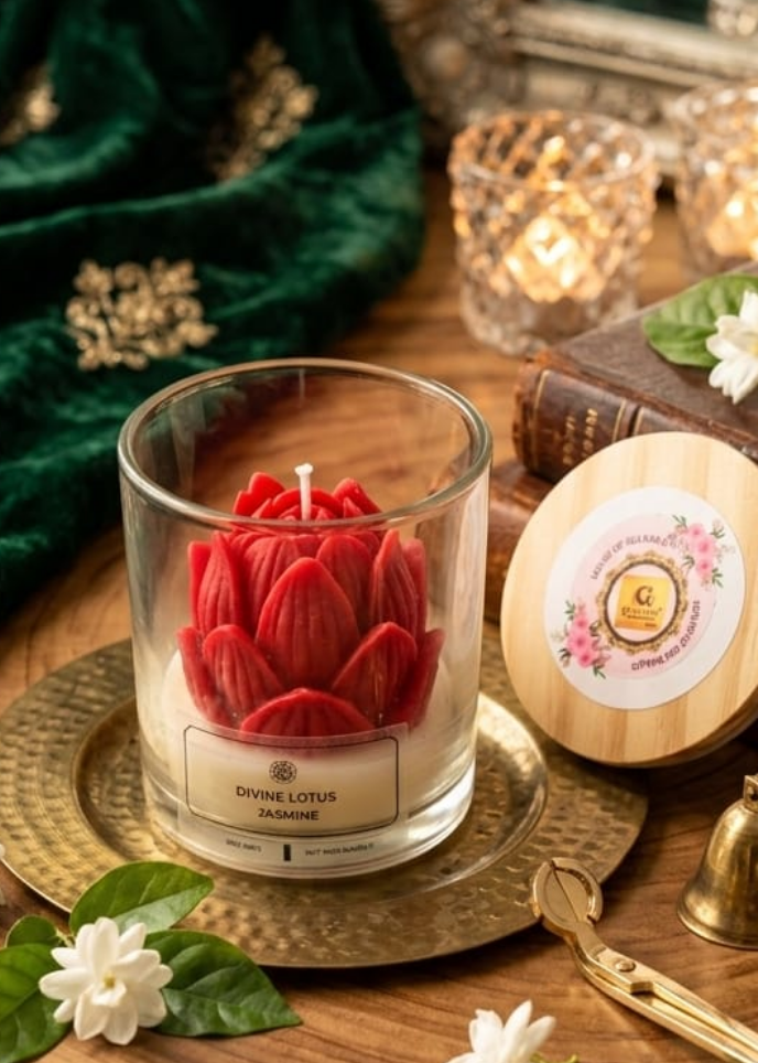 Glass candle with red flower design on a wooden surface with decorative items.