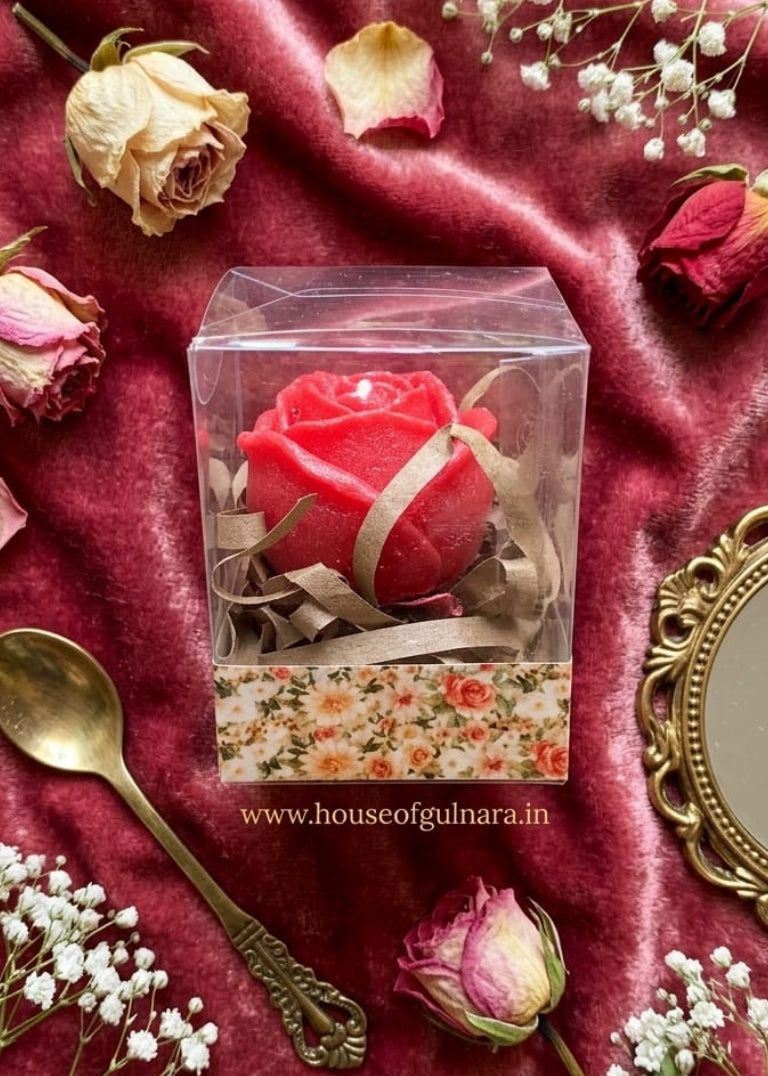 Red rose in a transparent box on a red fabric background with flowers and a spoon.