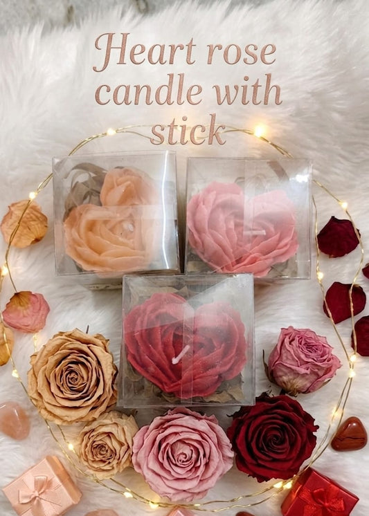 Heart-shaped rose candles with sticks on a decorative background with flowers and lights.