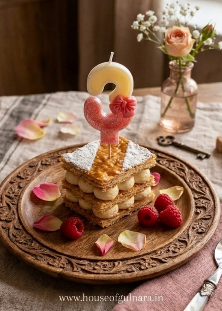 Stack of pancakes with a chicken-shaped candle on a wooden plate, surrounded by raspberries and flowers, on a table.