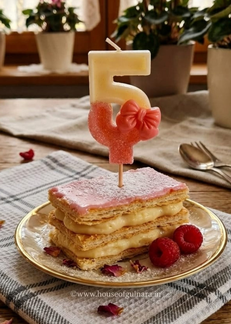 Pastry with a number 5 candle on a table with flowers in the background