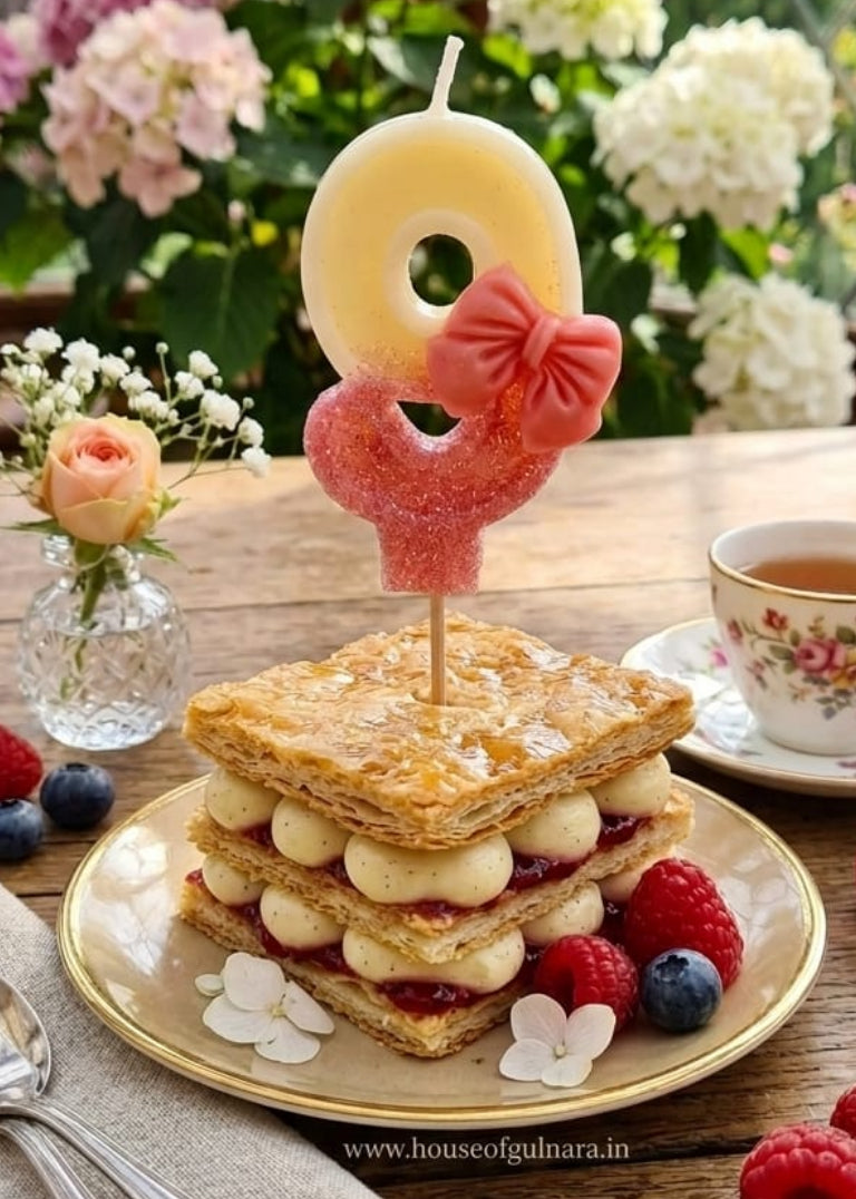 Stack of sandwiches with a number 9 candle on a wooden table with flowers and tea.