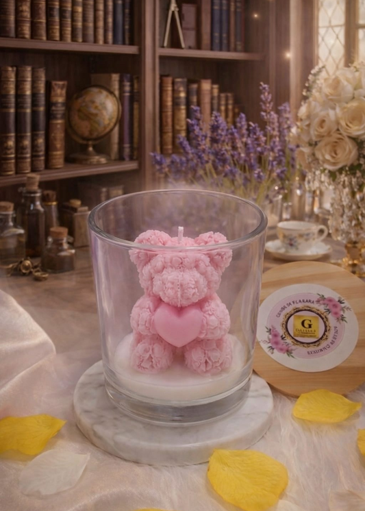Pink teddy bear candle in a glass holder on a table with decorative elements.