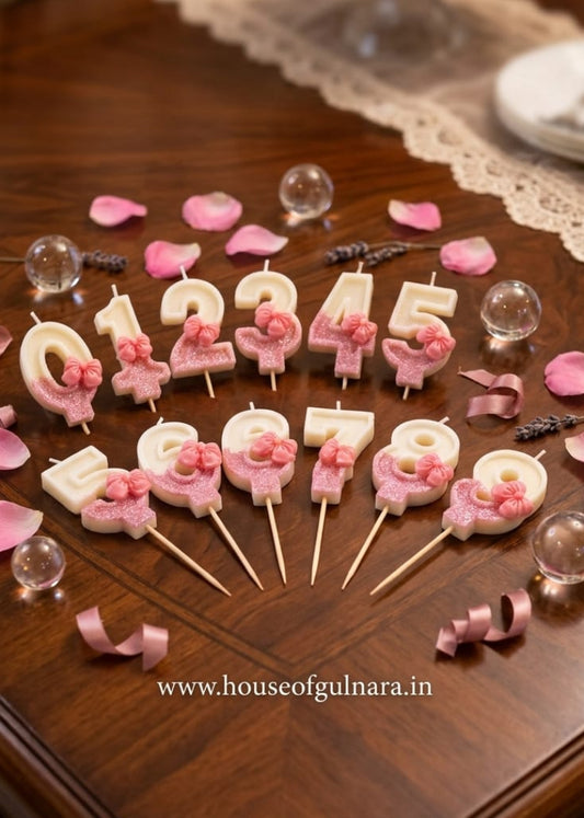 Decorative candles with numbers and flowers on sticks arranged on a wooden table.