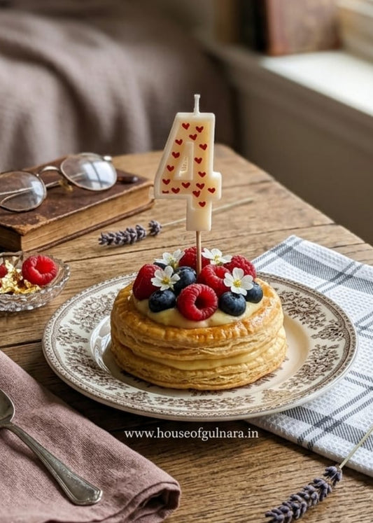 Small cake with berries on a wooden table with books and glasses in the background